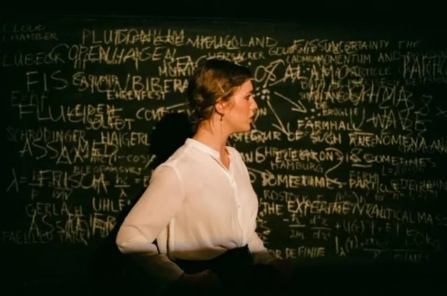 Margrethe in profile against the chalk-covered blackboard, half in shadow