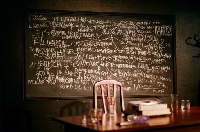 The empty set: a chalk-crammed blackboard above a wooden table holding a typewriter, books and glasses
