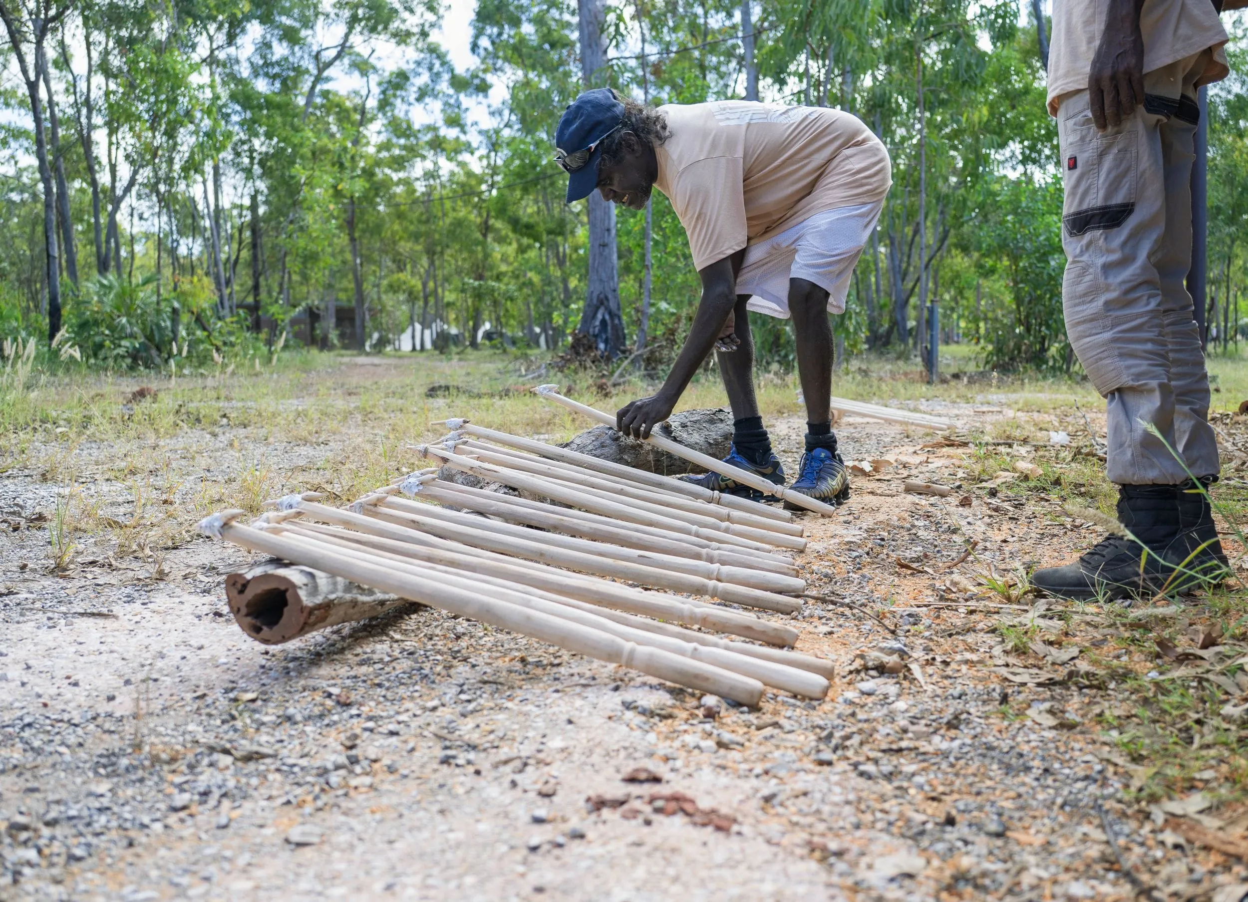 A man lays out freshly cut spear shafts on the track