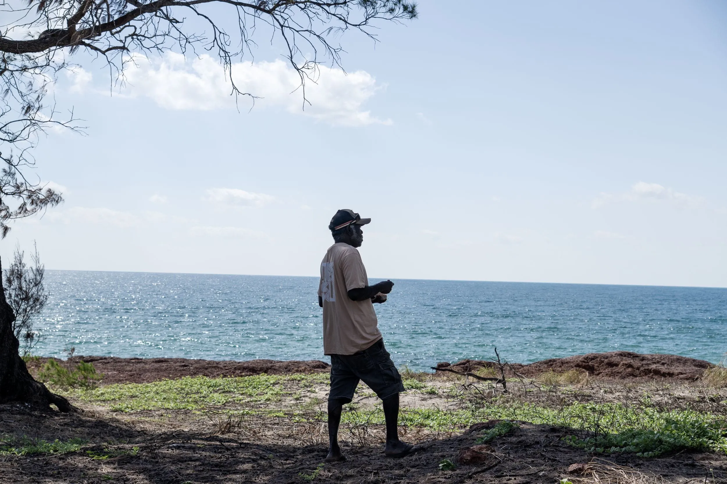 A man walks the clifftop above a turquoise sea, Arnhem Land coast
