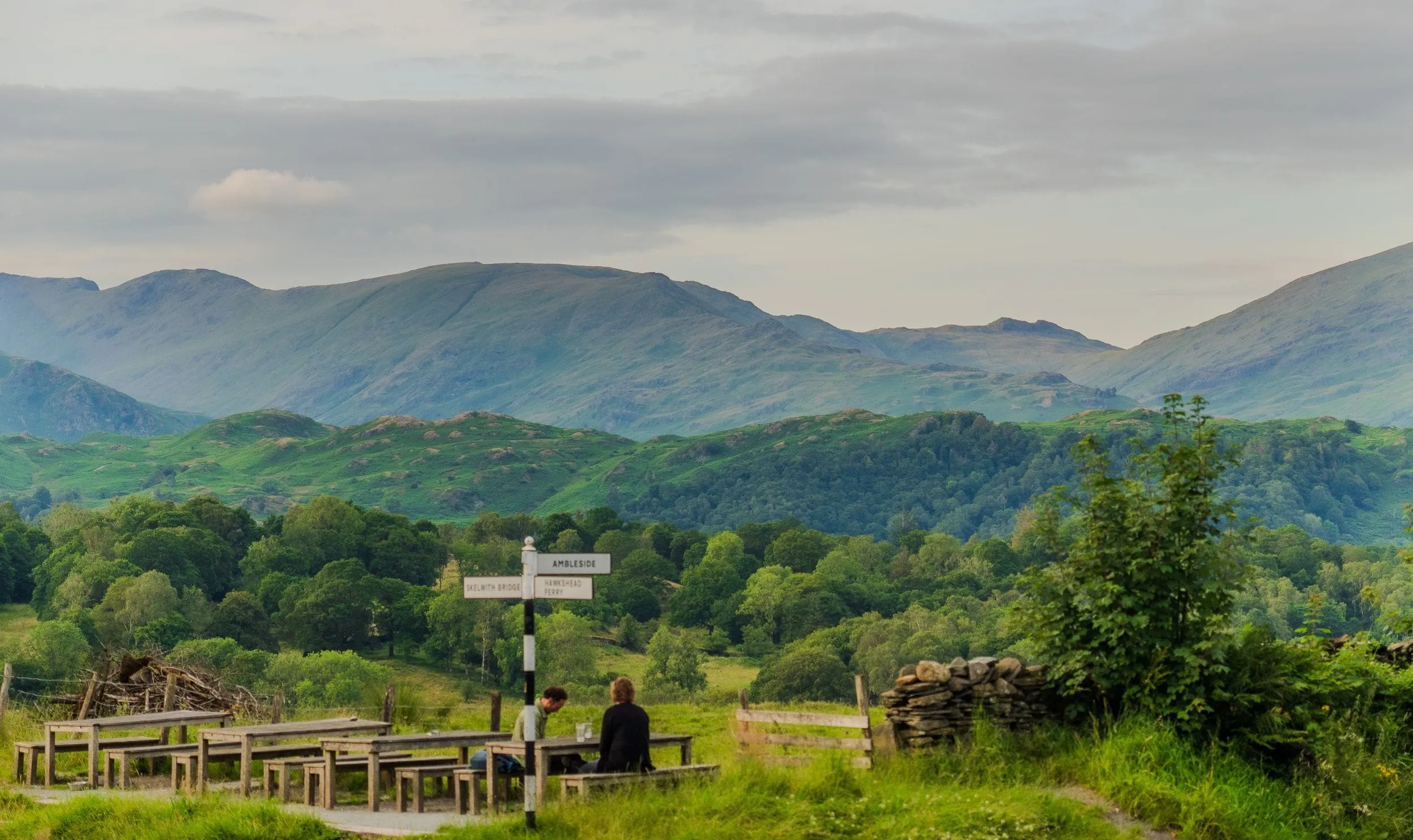 Picnic benches and a fingerpost to Ambleside beneath the fells, Lake District