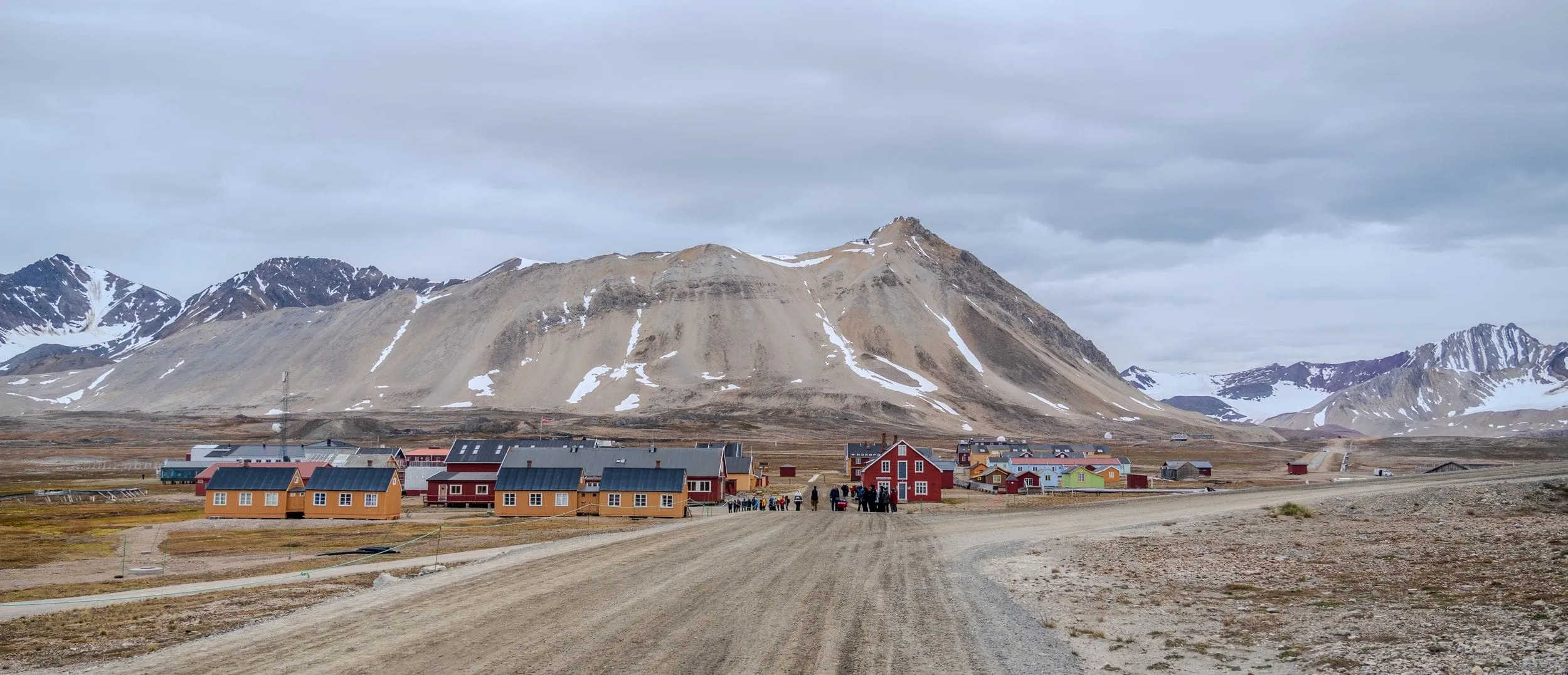 A cluster of painted wooden buildings beneath bare Arctic mountains, Svalbard