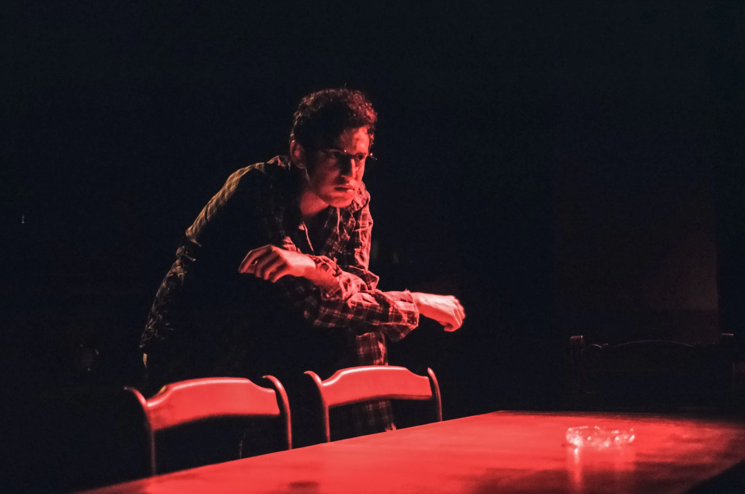 Stanley glowers over the backs of two chairs, drenched in red light